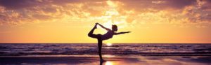 Frau macht Yoga am Strand bei Sonnenuntergang